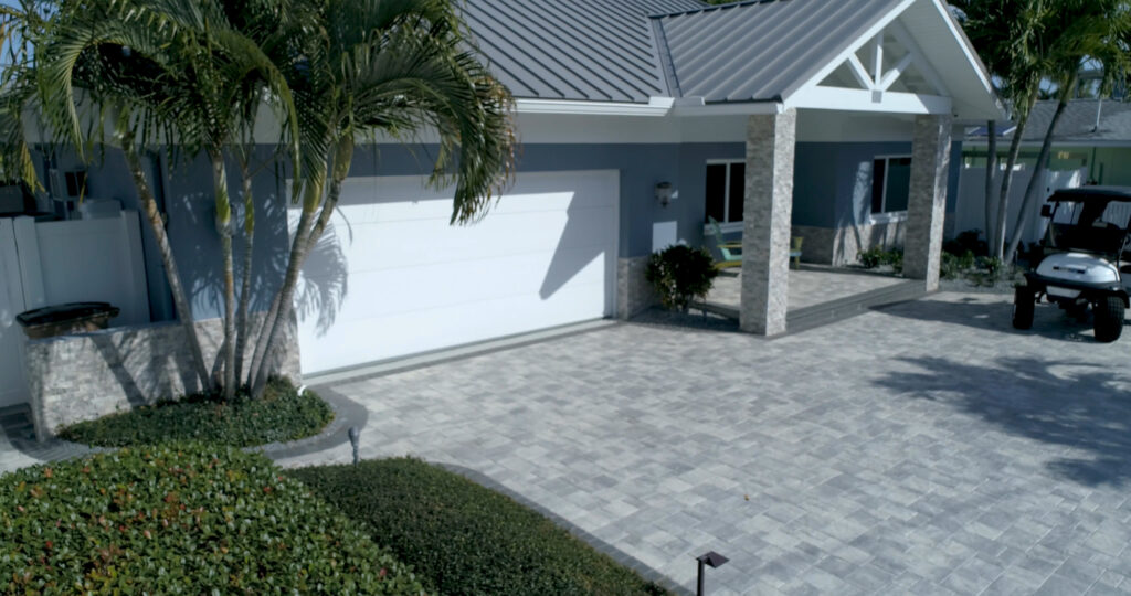 An image of a grey, paved driveway with steps leading up to the door.