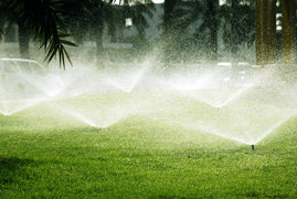 An image of an array of sprinklers in a green field.