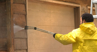 An image of a man pressure washing the front of a house.